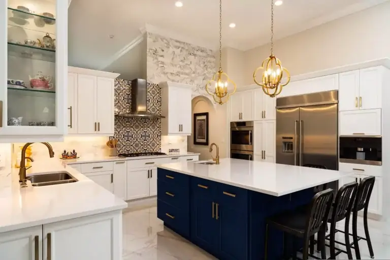 Renovated kitchen with a navy island, white cabinetry and pendant lights