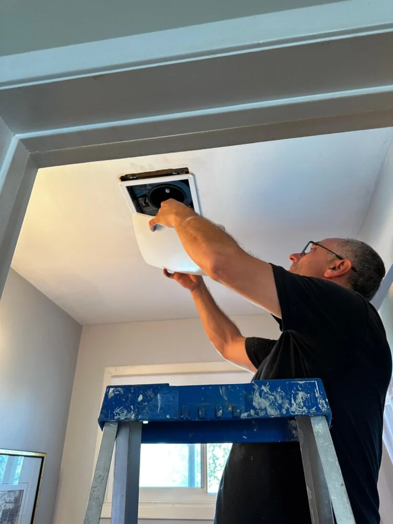 CNG technician installing a new bathroom exhaust fan grille in Mississauga