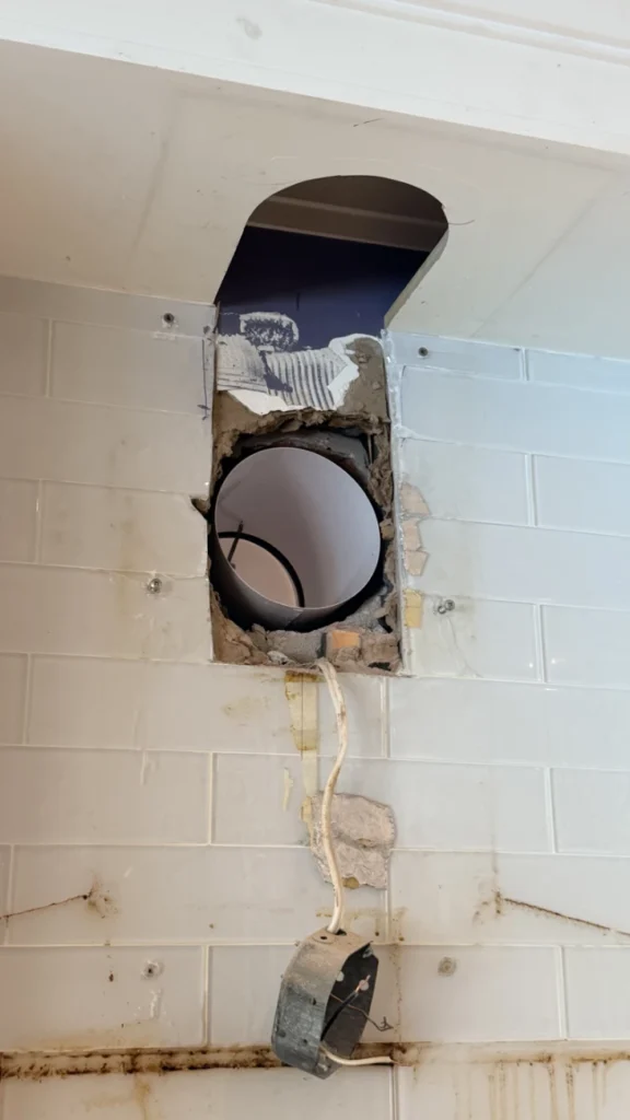 Range hood duct passing through the wall behind the cabinets