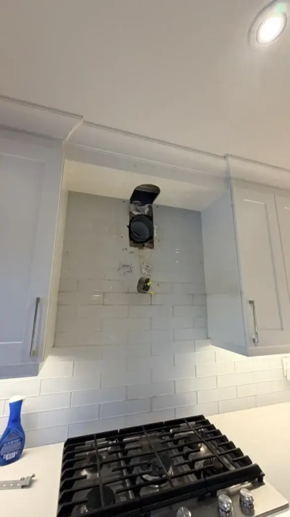 Range hood insert installed in the white kitchen cabinets