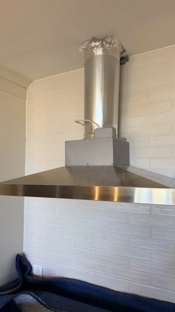 New stainless steel chimney range hood vented through the roof of an Uxbridge kitchen